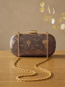 Beige and black luxury statement evening bag with gold clasp and chain sling.