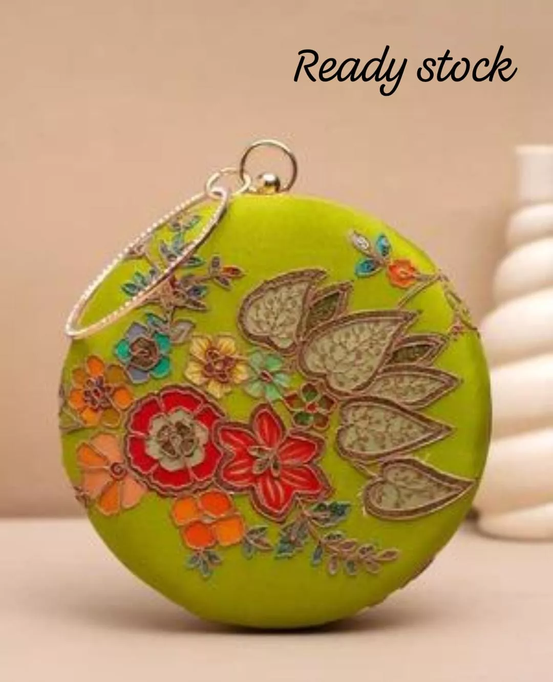 Clutiva Artisan Floral Embroidered Round Statement Clutch Clutiva round ethnic clutch available in rose pink and lime green, featuring intricate multi-color floral machine embroidery and a crystal-studded circle handle.